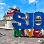 Colourful letter sign saying Vive SJO in square to the side of the National Theatre building, San Jose, Costa Rica