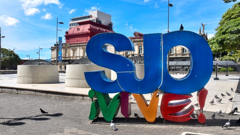 Colourful letter sign saying Vive SJO in square to the side of the National Theatre building, San Jose, Costa Rica
