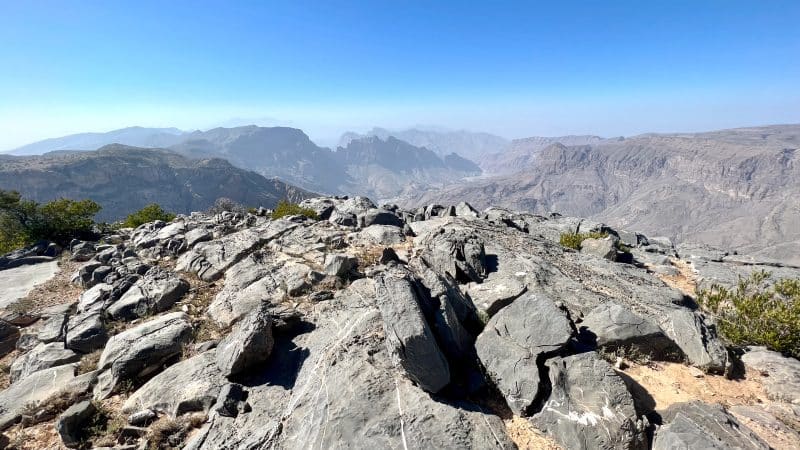 Rocky foreground, rocky mountain peaks in background. Blue sky