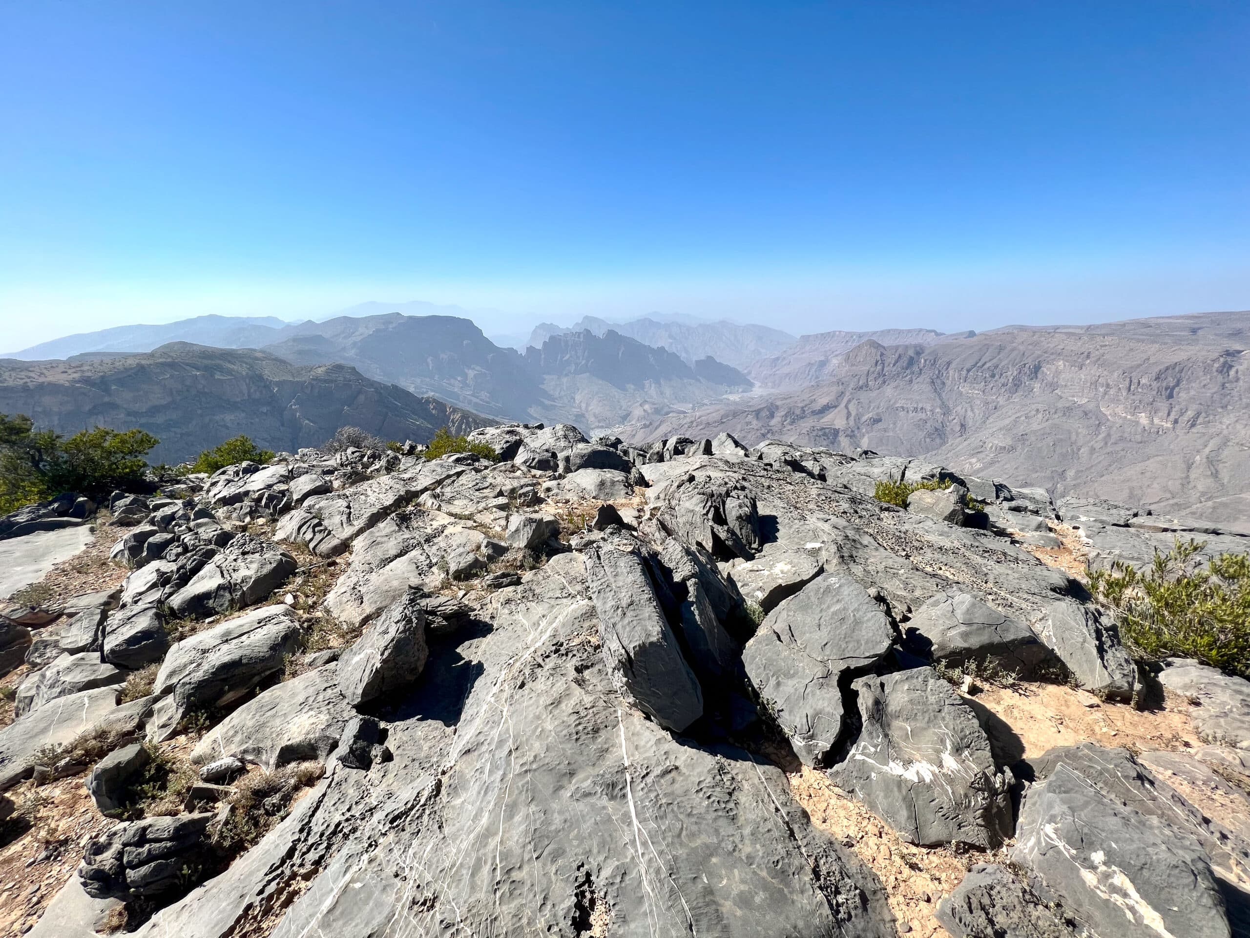 Rocky foreground, rocky mountain peaks in background. Blue sky