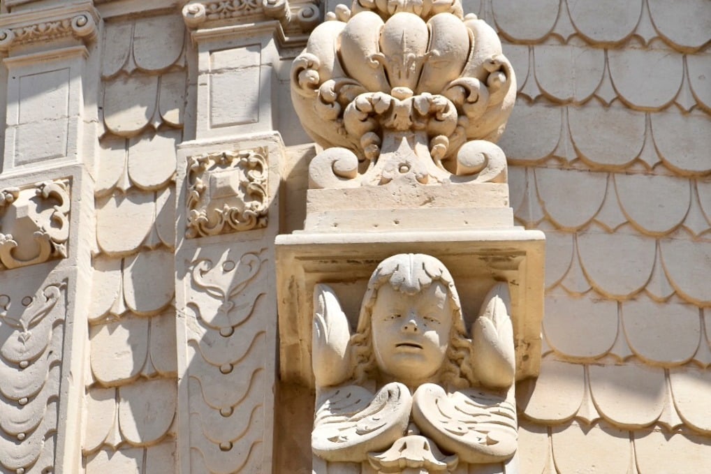 Sandstone carving in Baroque style outside Church. Features a cherub face over folded wings