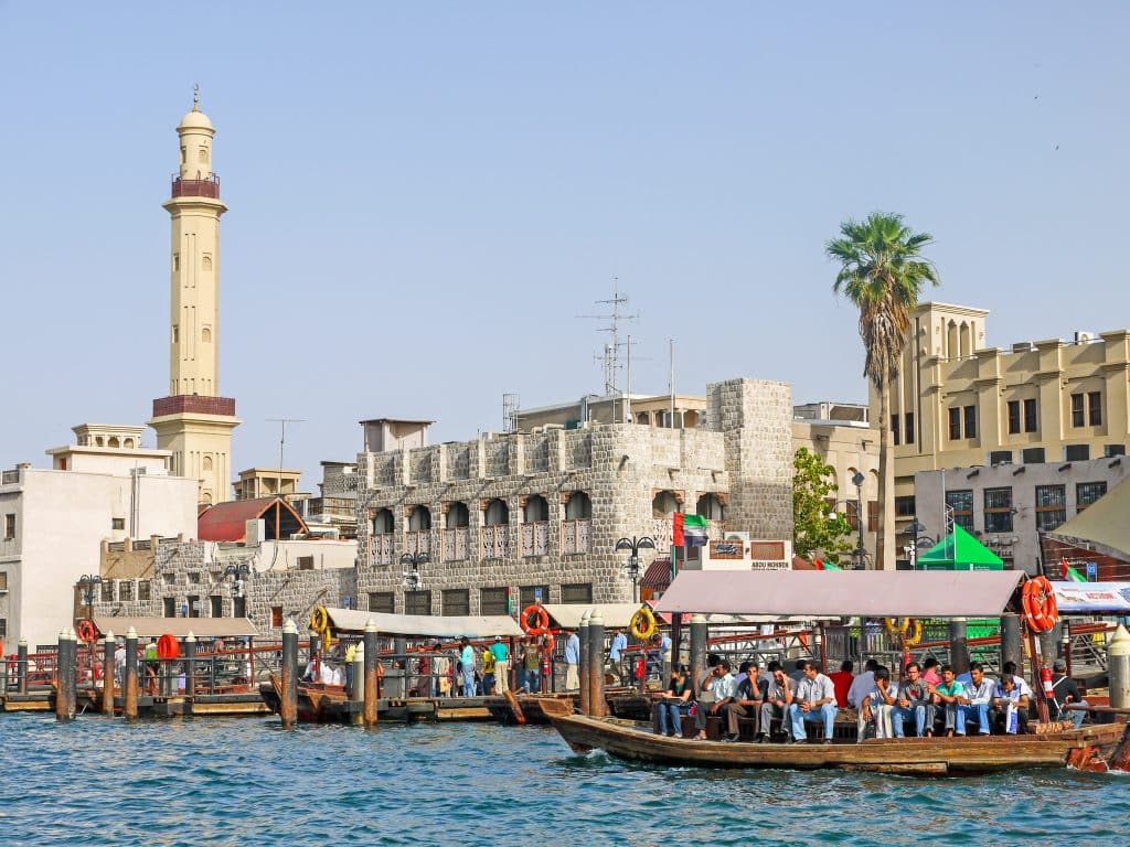 Old fashioned buildings with Arabic architecture with river in front and small wooden boats filled with passengers on the water