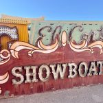 Old fashioned brown neon sign which spells ShowBoat in lightbulbs. Other signs behind with blue sky