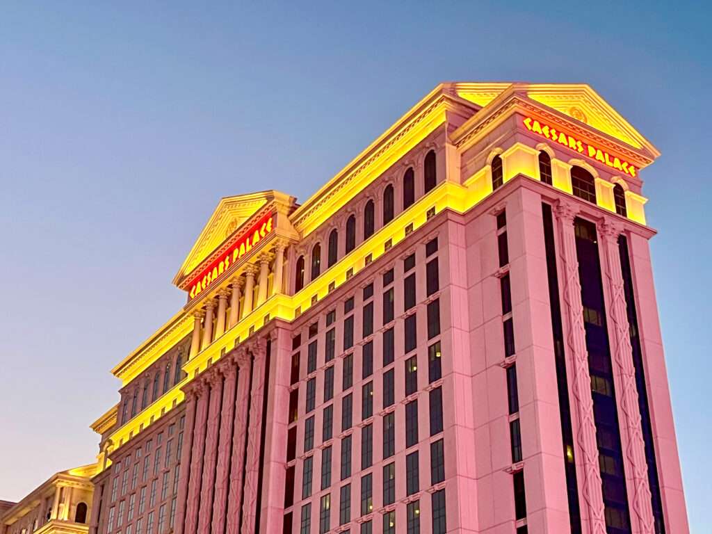 A large hotel is rising from the bottom right of the frame, illuminated with pink lighting. Yellow at the top., Disk blue sky above