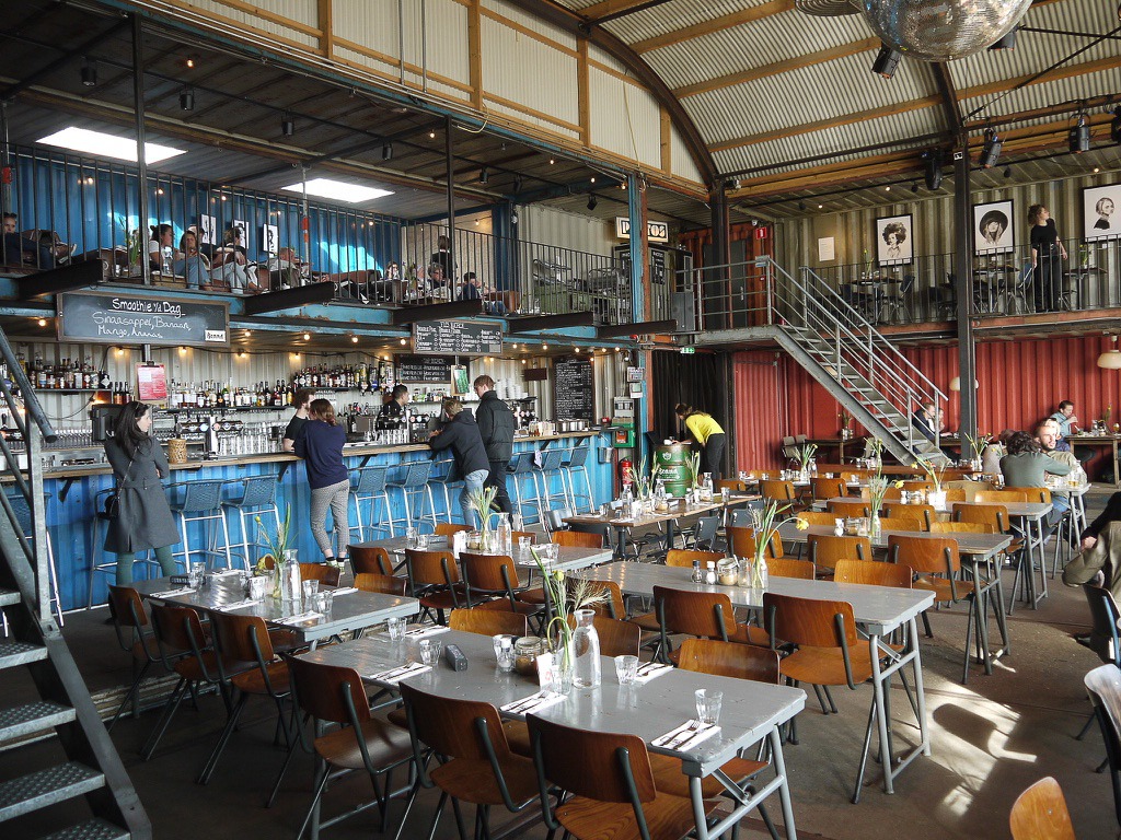 View across rows of tables and chairs in a cafe which looks to be in a warehouse or container