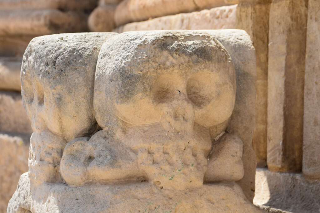 Sandstone block with carvings of skull facing the camera