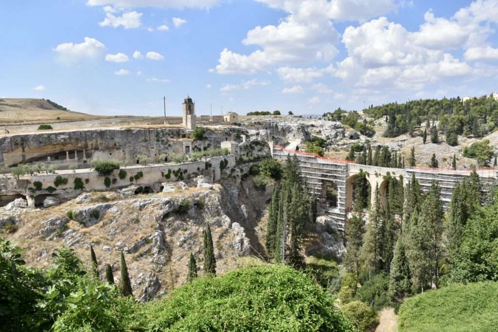 View across a Vally to a cliff with buildings on top and a tall bridge to the right