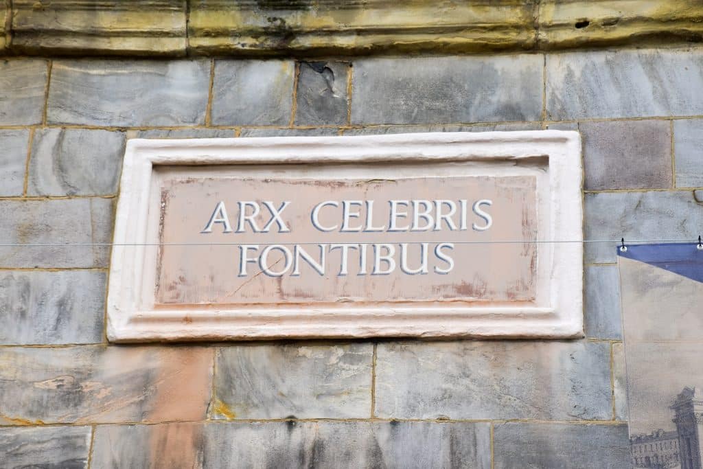 Stone brick wall featuring a rectangular stone plaque with the words Art Celebris Fontibus