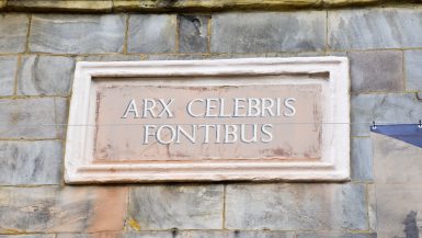 Stone brick wall featuring a rectangular stone plaque with the words Art Celebris Fontibus
