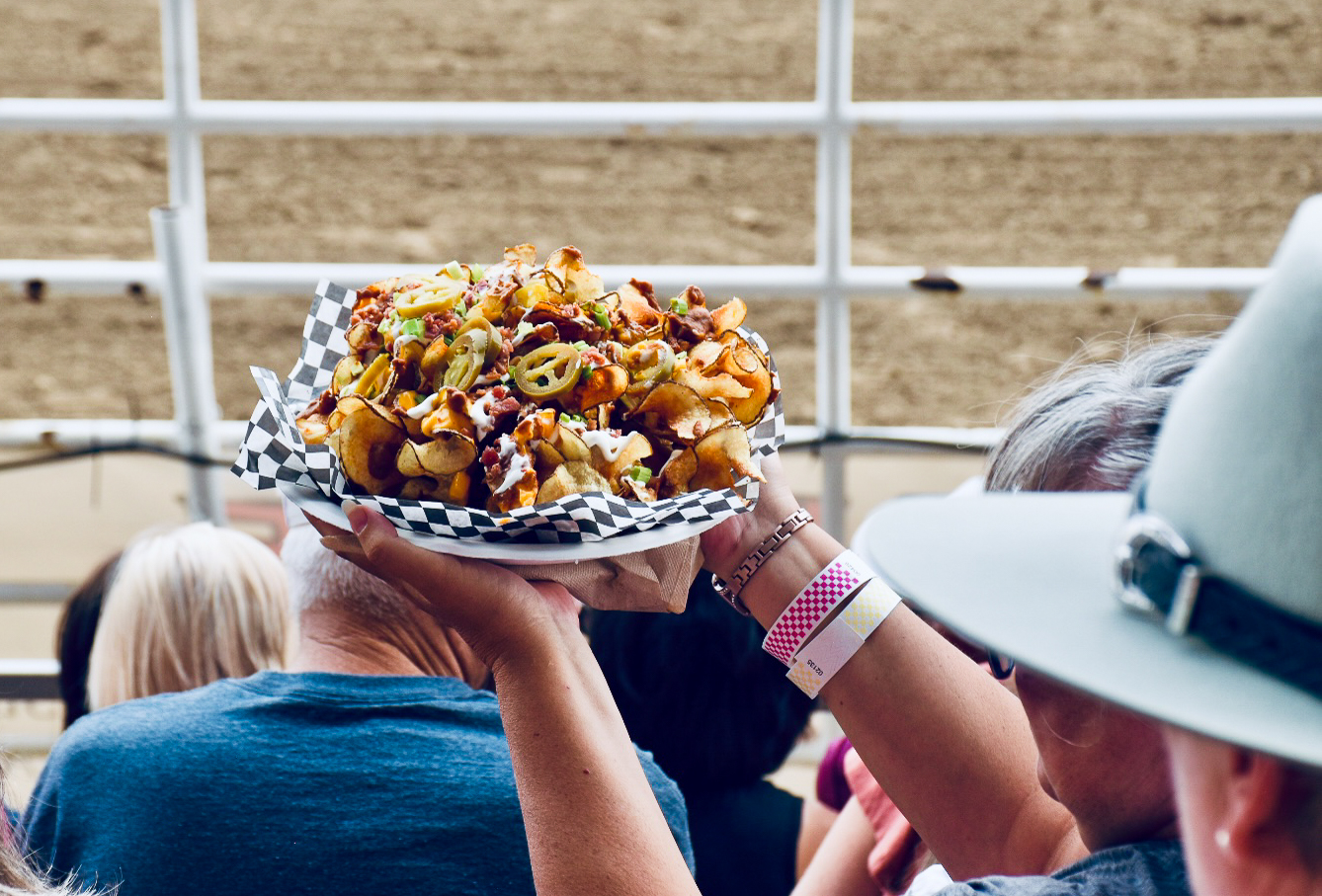 Two arms holding up a plate of loaded potato waffles, as if offering to a neighbour