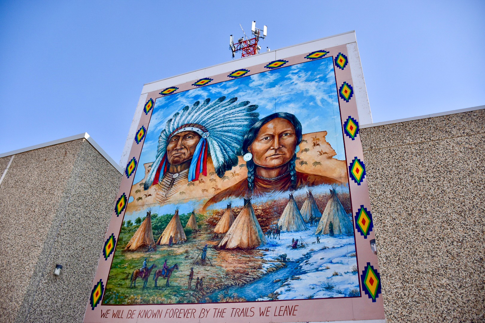 Multicoloured mural of Native Americans on side of plain brick building.  