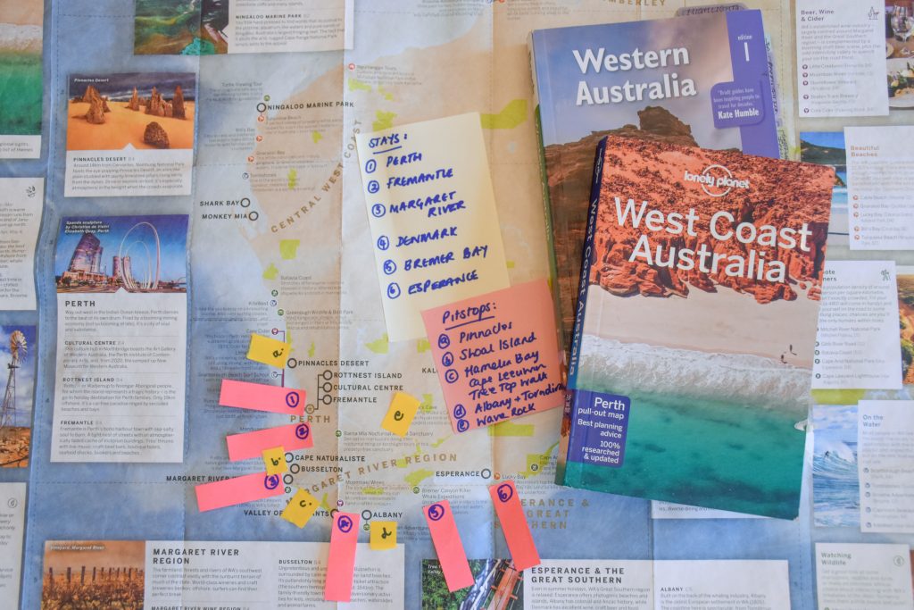 Tourist map of Western Australia decorated with information panels, and post it notes highlighting places to stop. Two travel guide books for Western Australia sit on top of the map