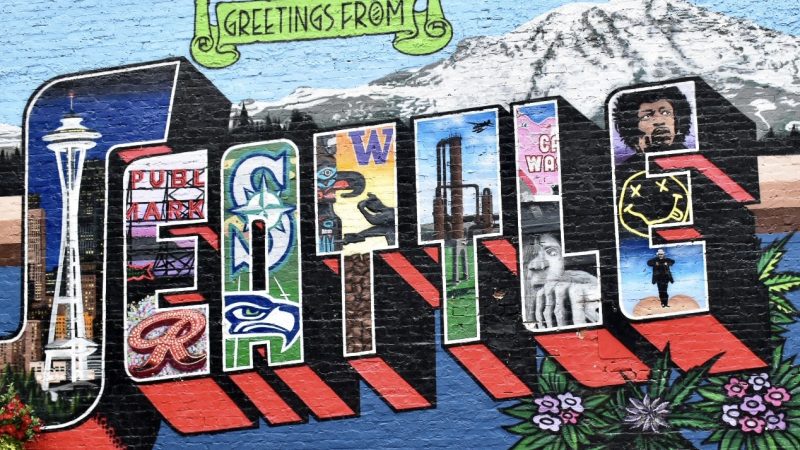 A multicoloured wall mural features 'Greetings from SEATTLE'. there is a mountain behind the word Seattle