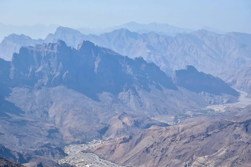 Hazy landscape from top of rocky range of mountains, down into valley