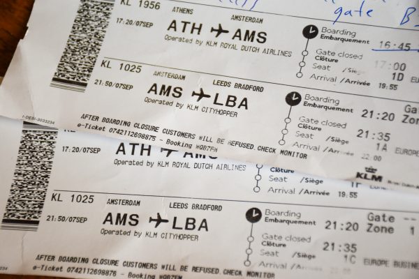 Frame is filled with close ups of two white airline boarding cards - one along the bottom and one at an angle across the top right. Printed writing shows that they are for a flight from Amsterdam to Leeds Bradford on KLM CityHopper