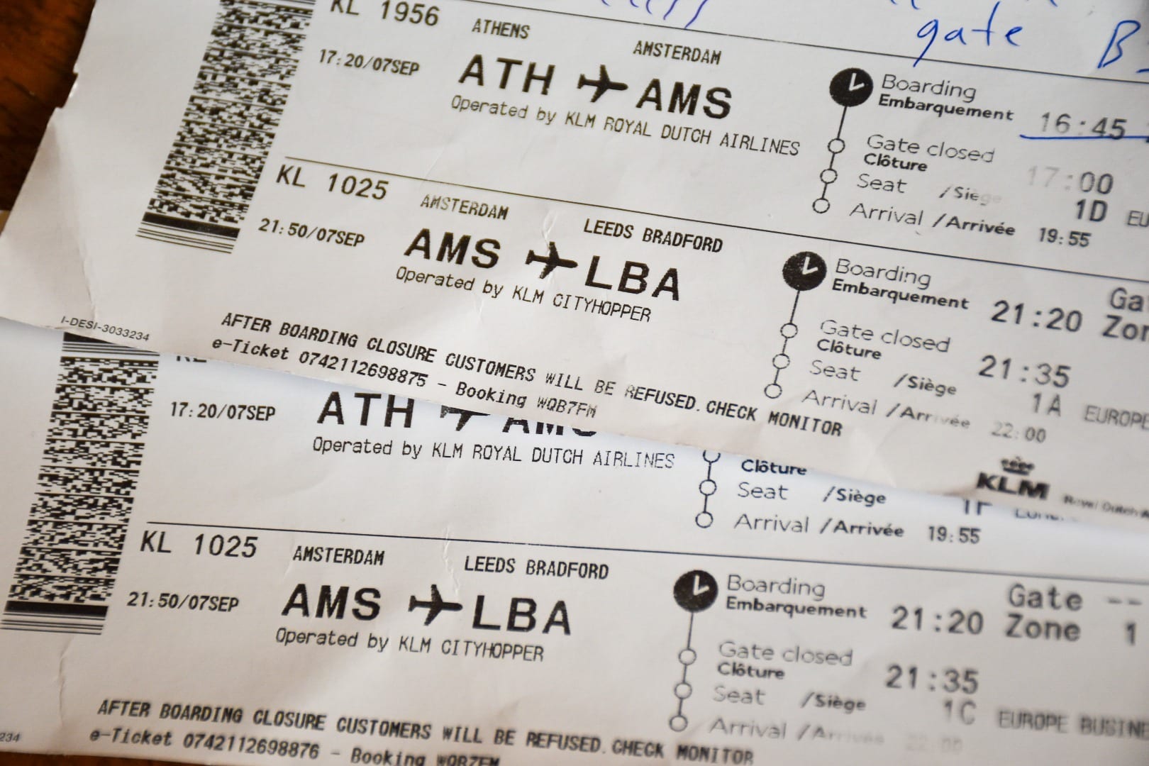 Frame is filled with close ups of two white airline boarding cards - one along the bottom and one at an angle across the top right. Printed writing shows that they are for a flight from Amsterdam to Leeds Bradford on KLM CityHopper