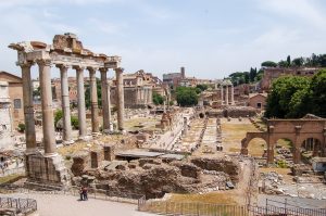 View down onto an area of ancient ruins. The tall columns of a temple stand to the left hand side