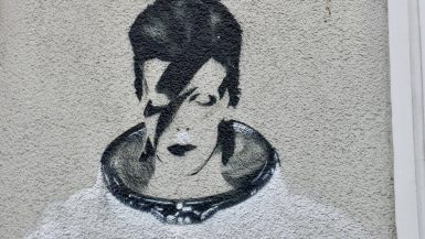 Spray painted mural / graffiti picture of David Bowie in space suit on a white wall