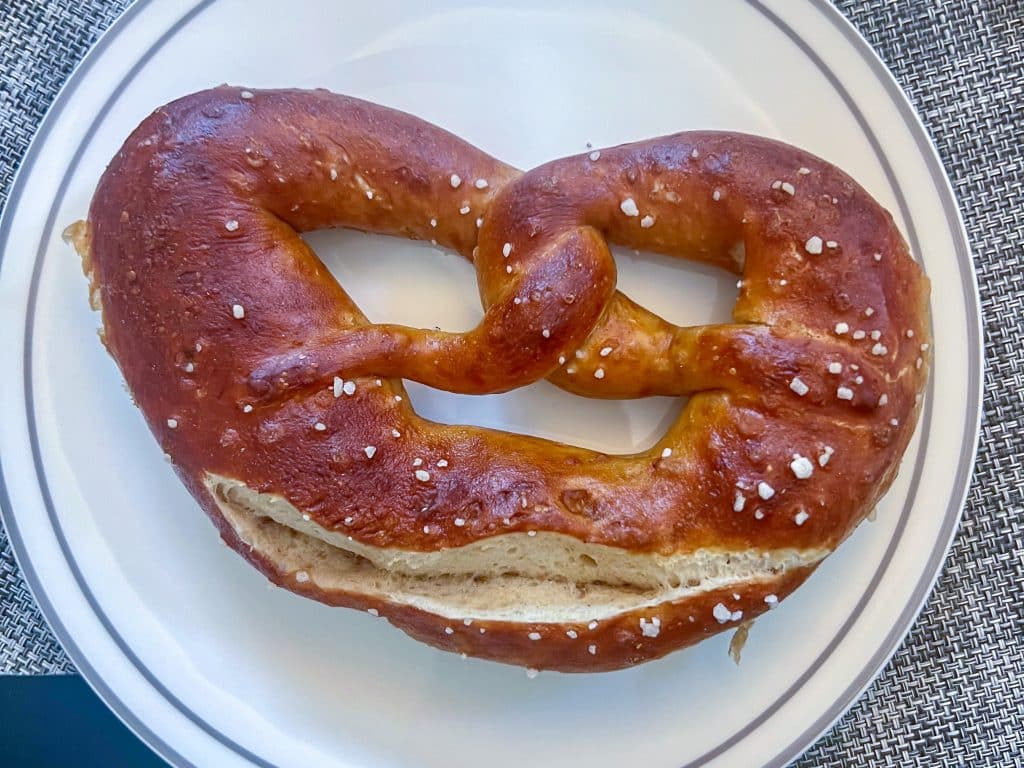 Large pretzel on a white plate on a grey tablecloth