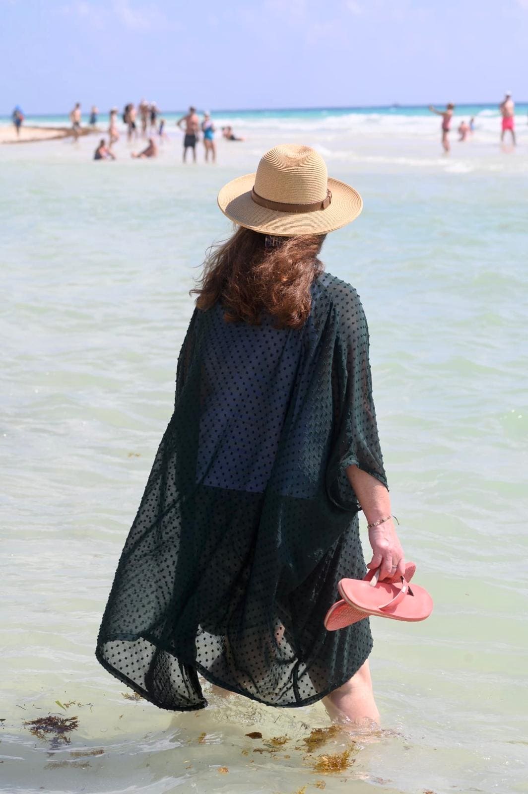 Woman standing in ocean wearing beach dress