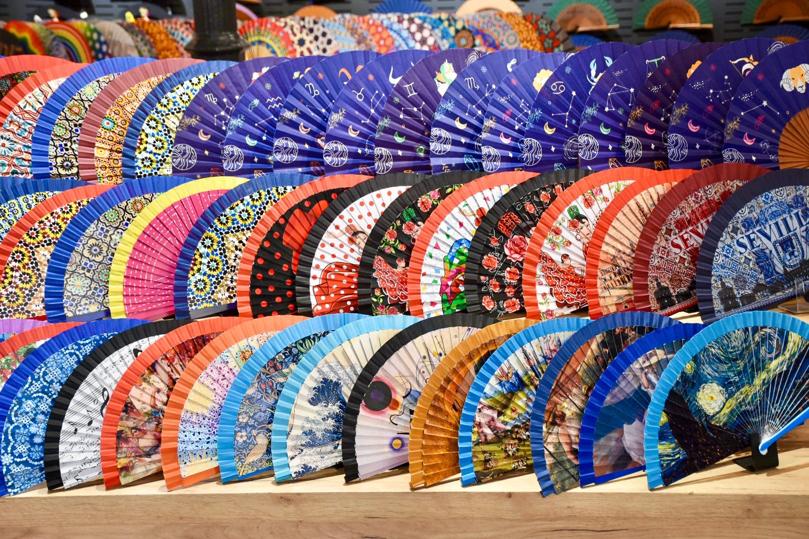 3 rows of open paper hand fans arranged horizontally to display the colourful prints on the fans