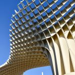 Clear blue sky with modern structure of interconnected strips leading up from the bottom right hand side to the left.