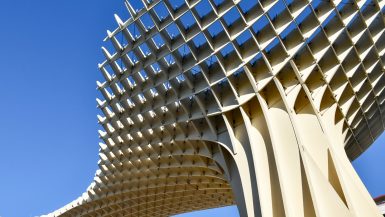 Clear blue sky with modern structure of interconnected strips leading up from the bottom right hand side to the left.