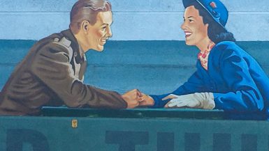 Mural of a soldier on the left looking at a lady in blue hat and jacket to the right. They are holding hands and smiling at each other. Stipes of blue and jade green colour in background
