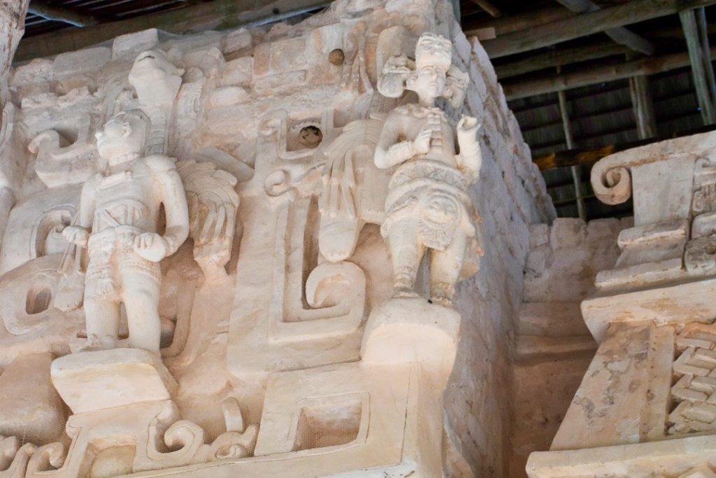 Close up of carvings of two warriors on the side of a buildings. The stone is white and clean.