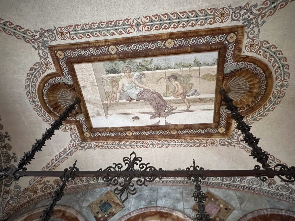 Looking up at a beautiful painting on the ceiling featuring a lady and two cherub boys