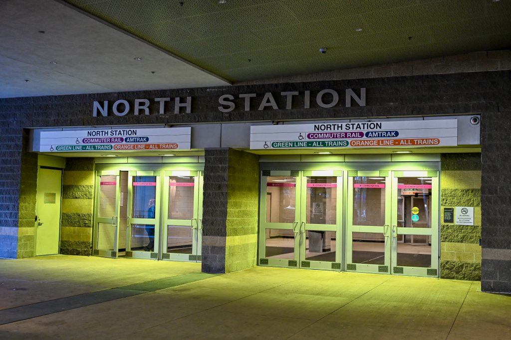 An eerie scene of two sets of double doors entering North Station. The doors are bathed in green light from above. Signs above the door indicate that it's a railway station - commuter rail, all trains.