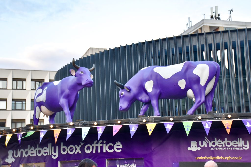a black roof over a sign for a box office with purple cows on the roof