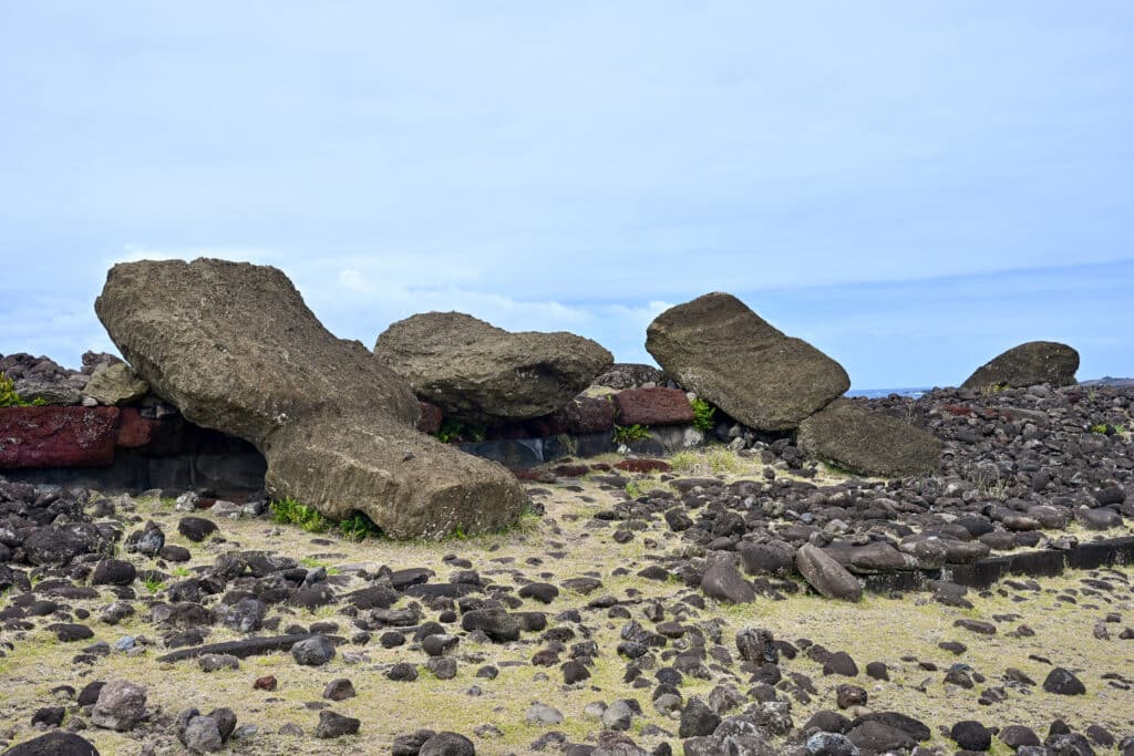 Pale green field covered with rocks and stones. Large rocky statues on the horizon. Pale blue sky above