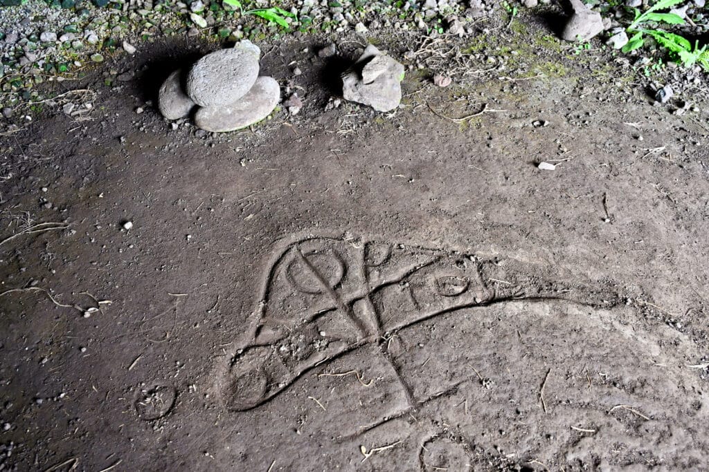 Photo of the floor with an indigenous drawing carved in the stone of a triangular shape