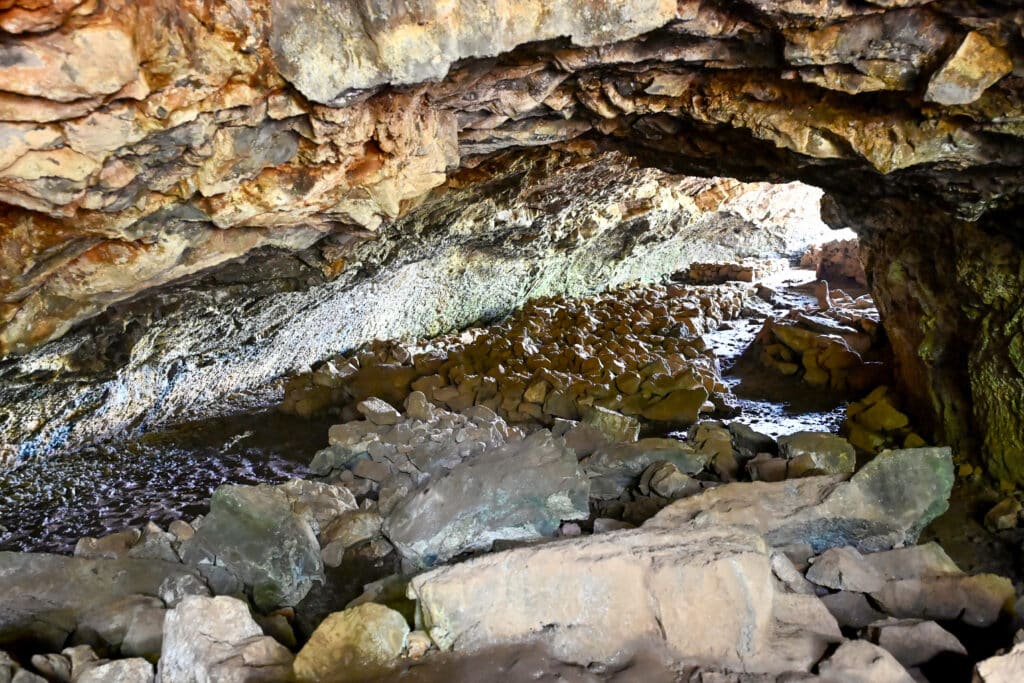 Inside a large rocky cave. Looking through a tub with rocks on the ground and overhead