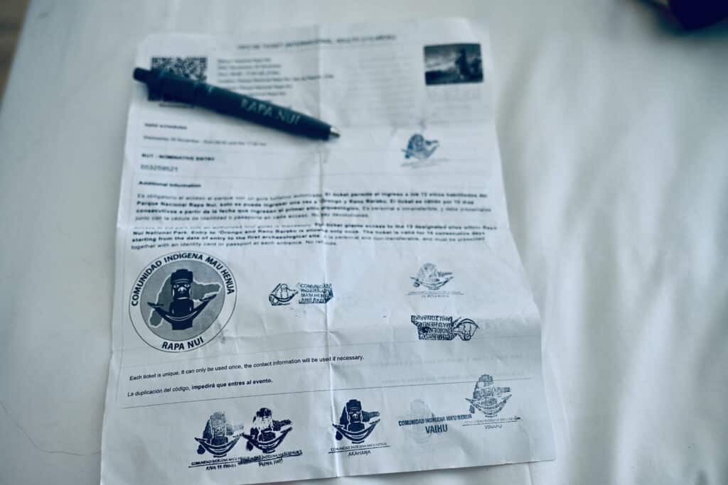 A white print out sits on a white background. It is full of printed information and stamps. Pen on top which says Rapa Nui on it. Could be national park stamps
