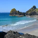 A gorgeous cove - sandy beach with rocks on the sand. Turquoise and blue sea.