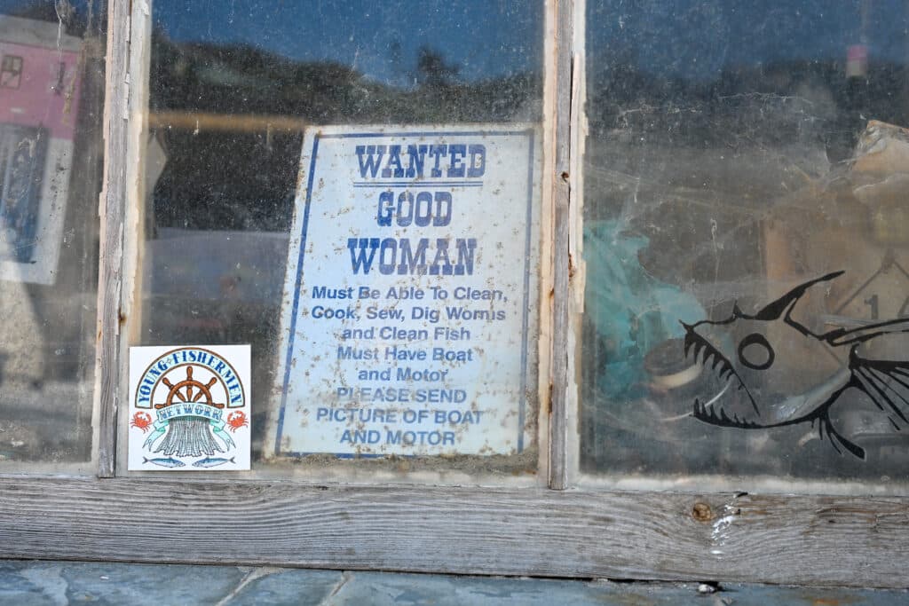 Sign in a dirty window saying Wanted Good Woman - with fishing skills!