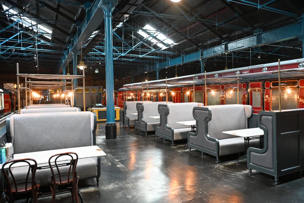 Indoor cafe which looks like a train carriage. Inside a train shed.