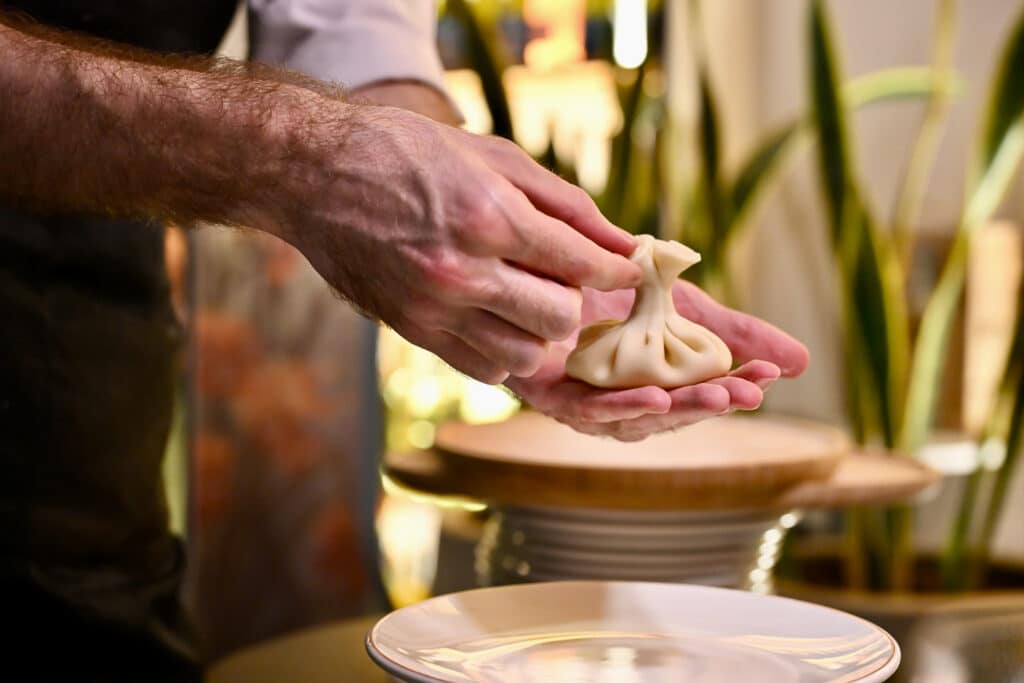 Pair of hands holds pastry dumpling up for demonstration