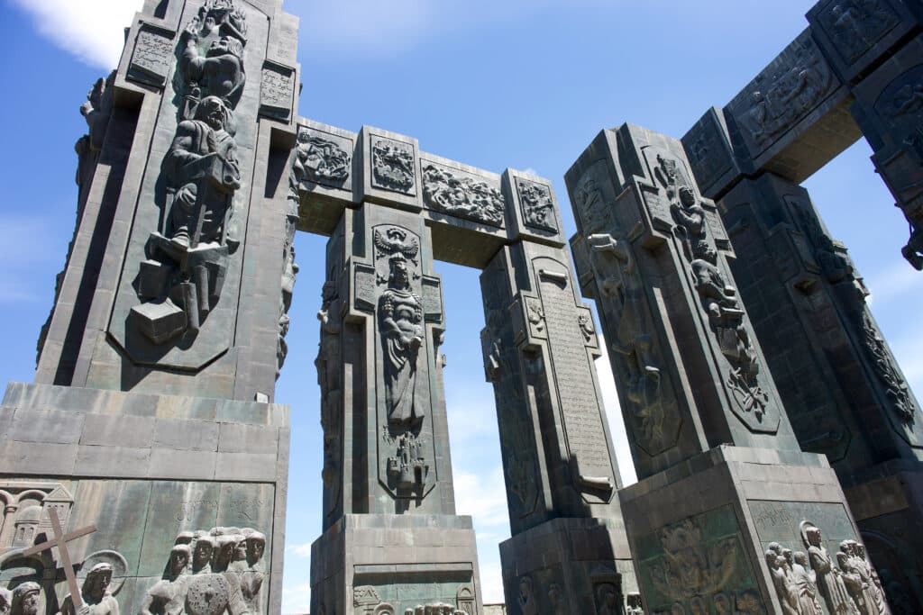 Four stone pillars and connecting bars covered in carvings of people and events.