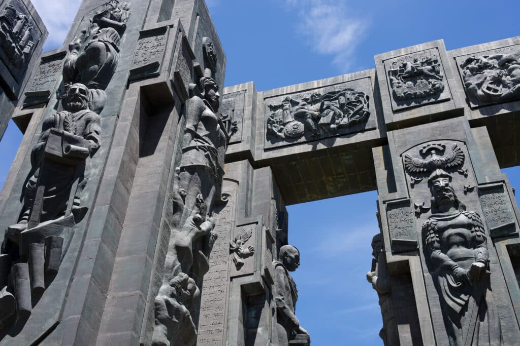 Two stone pillars and connecting bar covered in carvings of people and events.