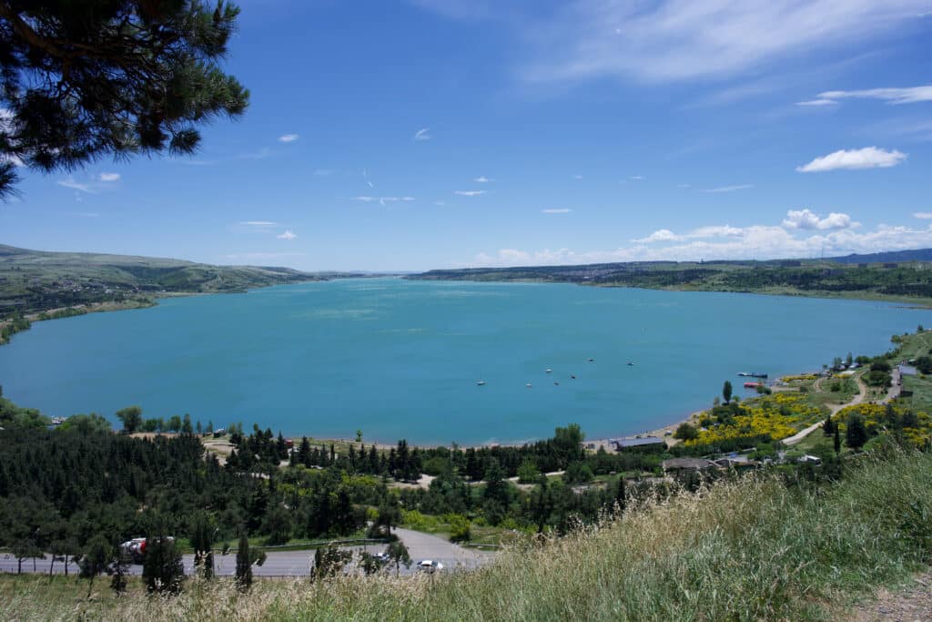 View of a blue lake surrounded by grassy banks.