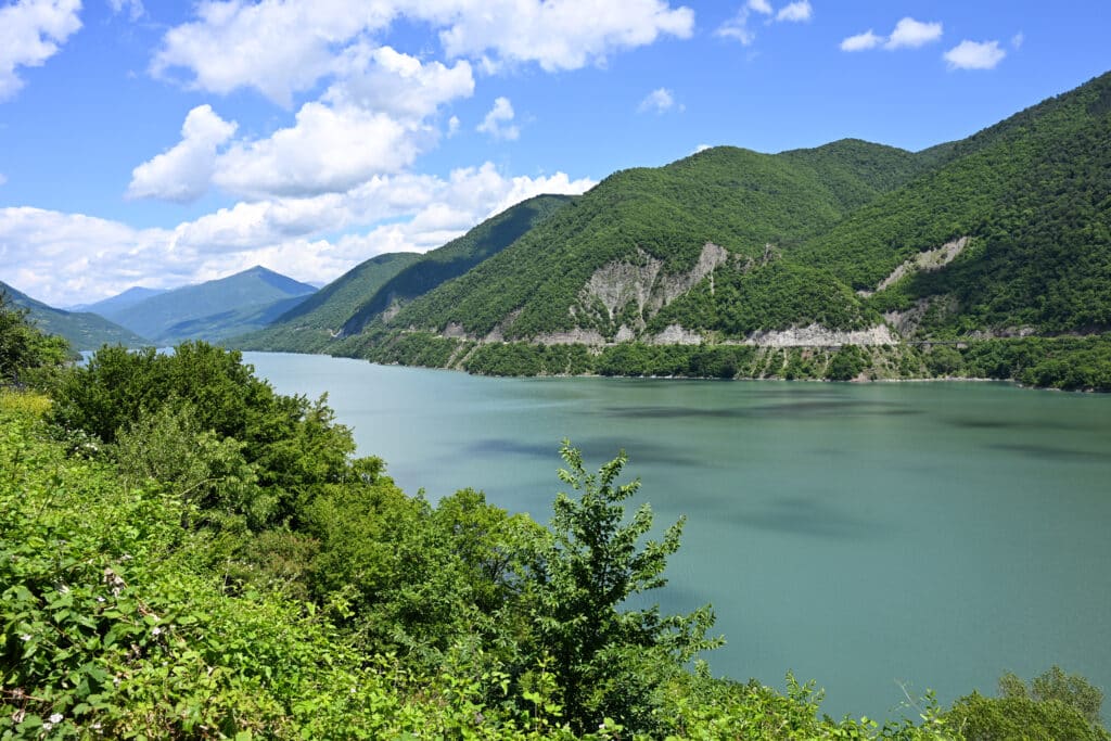 Turquoise body of water (lake, reservoir, fjord) with tree covered hills surrounding