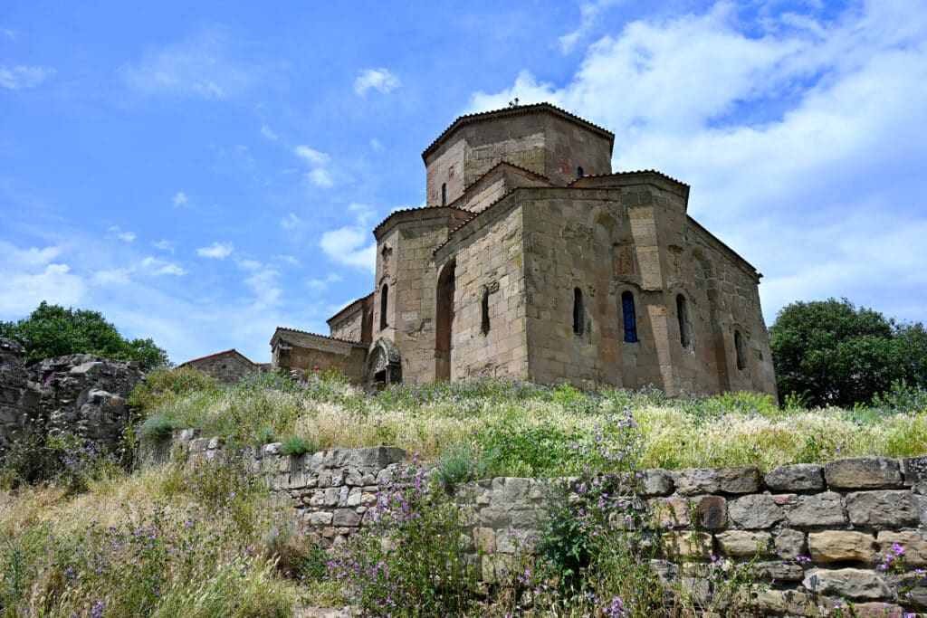 Looking up at a stone church. Grass in front and blue sky behind.