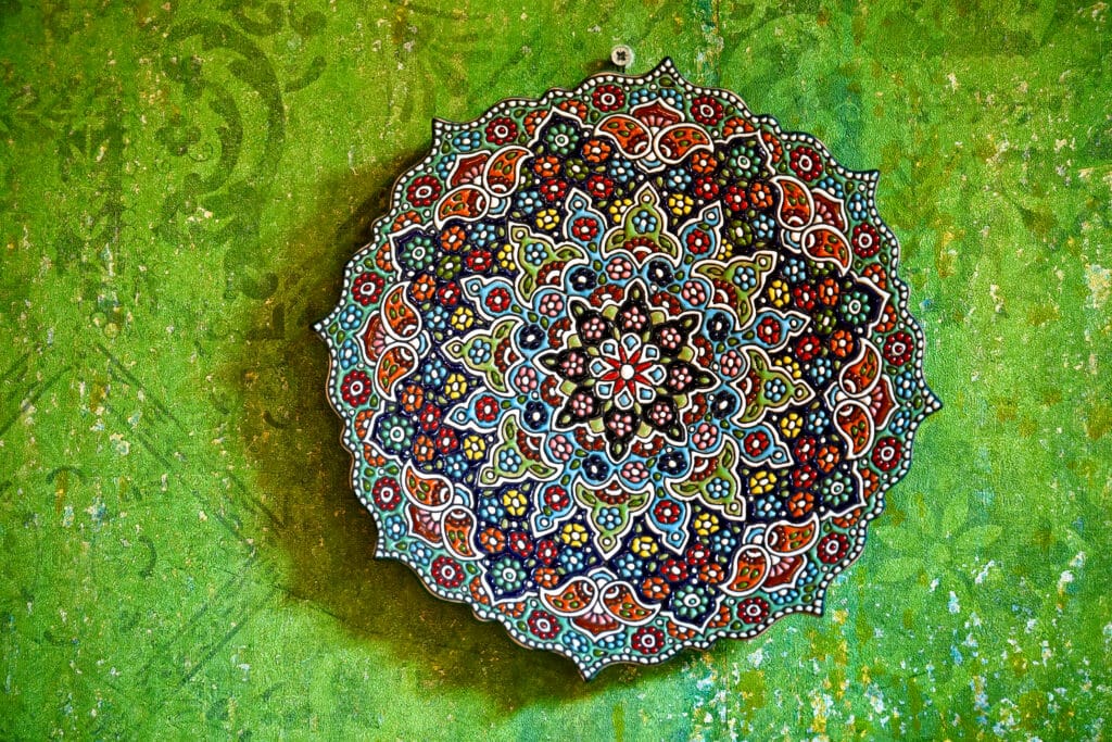 Multicoloured ornate circular plate mounted on a green wall.