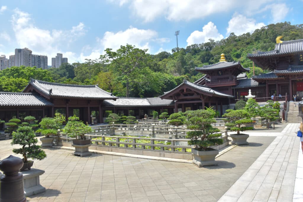 Low lying wooden buildings with Chinese pagoda shaped roofs across middle of frame