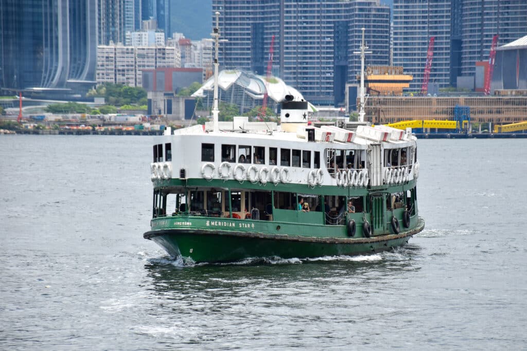 A green ferry with white roof approaches the left of frame