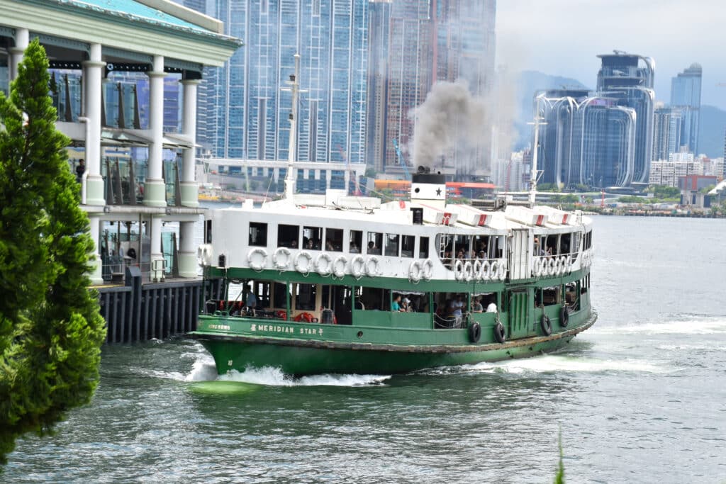 A green ferry with white roof approaches the left of frame
