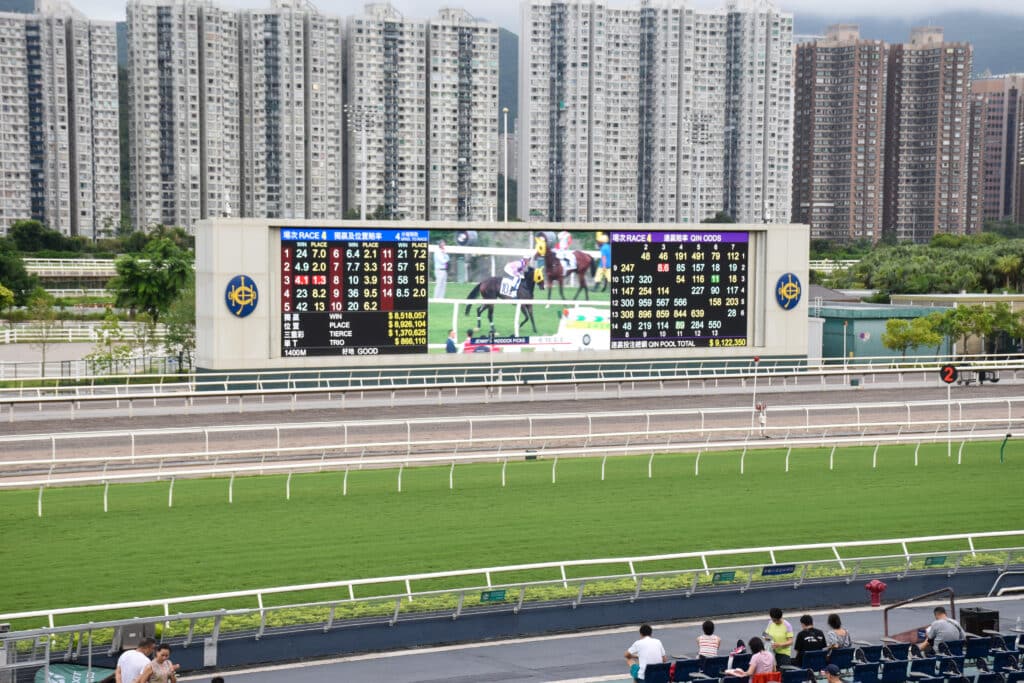 Horseracing scoreboard beind racetrack. Block of flats behind